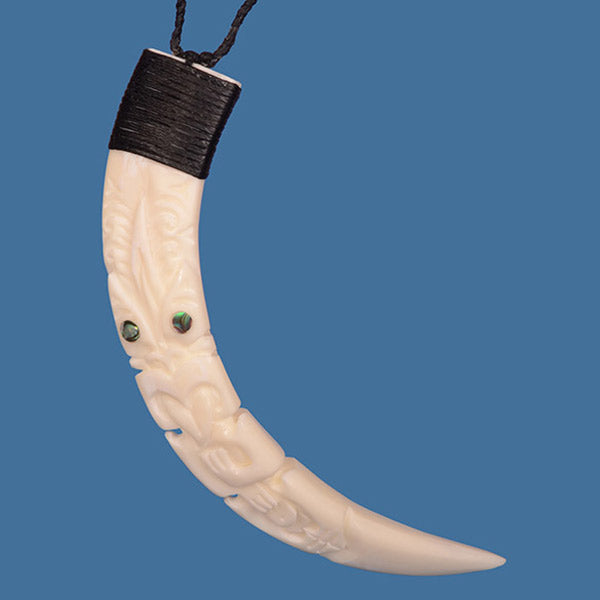 Hand-carved Tiki Silhouette Pig Tusk Pendant with Paua shell eyes, blending Maori artistry and modern style on a wax cord.