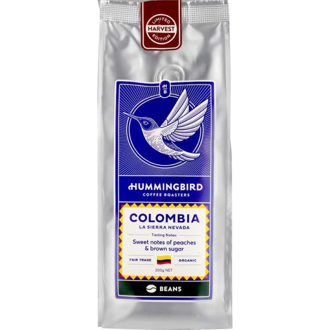 Hummingbird Fair Trade Organic Whole Bean Coffee from Colombia, featuring sweet peach and brown sugar notes in a 200g pack.