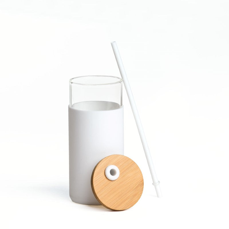 Elegant white borosilicate glass bottle with bamboo lid, silicone sleeve, and matching straw for stylish hydration on-the-go.