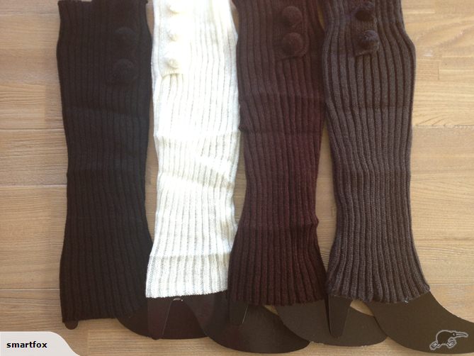 Stylish white cable knit leg warmers with pom-poms, soft and warm, perfect for winter fashion and cozy comfort.