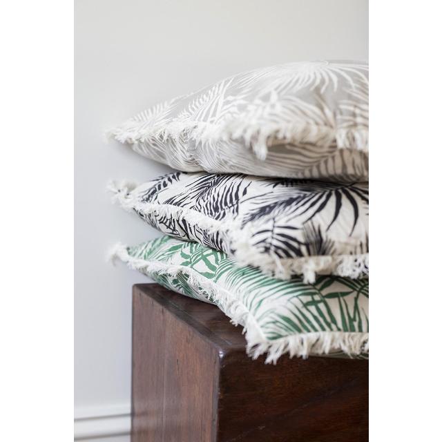 Cushion with bold palm print and playful fringe, adding coastal charm to any decor in a rich Raven hue.