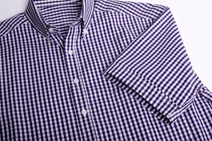 Vibrant purple short sleeve shirt with check pattern, button collar, action back, and front pocket for versatile styling.