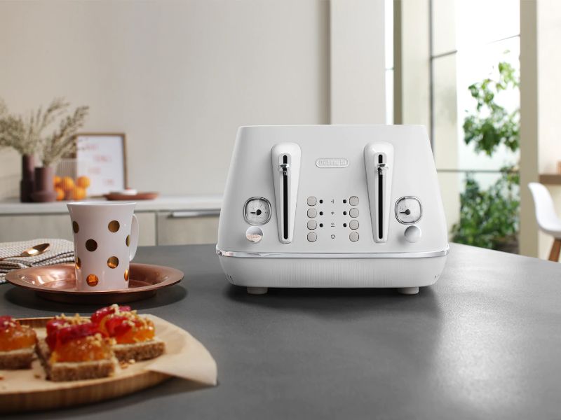 DeLonghi Distinta Moments 4 Slice Toaster in white, featuring dual controls, 6 browning levels, and elegant stainless steel design.