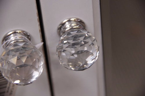 Elegant mirrored cabinet with bevelled surfaces and crystal knobs, perfect for stylish storage in any room.