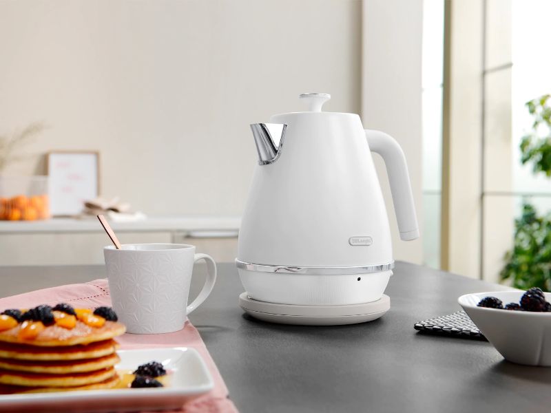 DeLonghi Distinta Moments Kettle in White, featuring a metallic finish, 1.7L capacity, swivel base, and safety features.