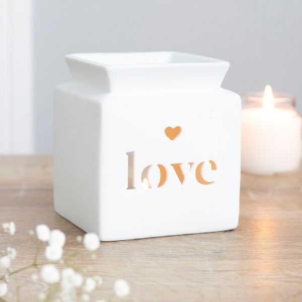 White ceramic oil burner with heart cut-out and 'love' text, ideal for enhancing home ambiance with soothing scents.