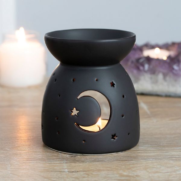 Black ceramic oil burner with crescent moon and star cut-outs, perfect for warming fragrance oils and creating ambiance.