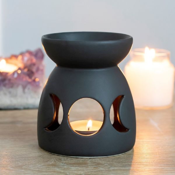 Black ceramic oil burner with triple moon cut-out design for aromatherapy, perfect for relaxation and spiritual ambiance.