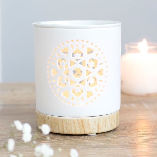 White ceramic oil burner with intricate mandala cut-out design and wood-effect base, perfect for aromatherapy and home decor.