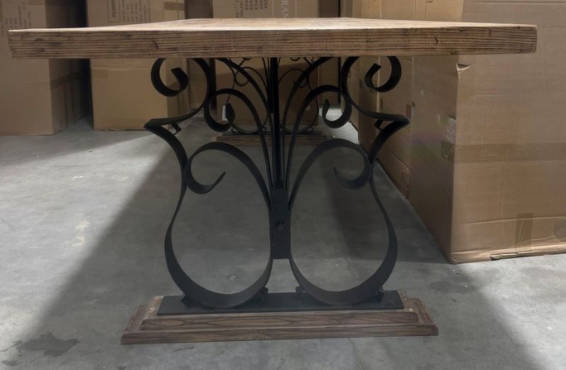 Rustic reclaimed oak dining table with sleek black iron legs, accommodating up to 8 diners, blending elegance and durability.