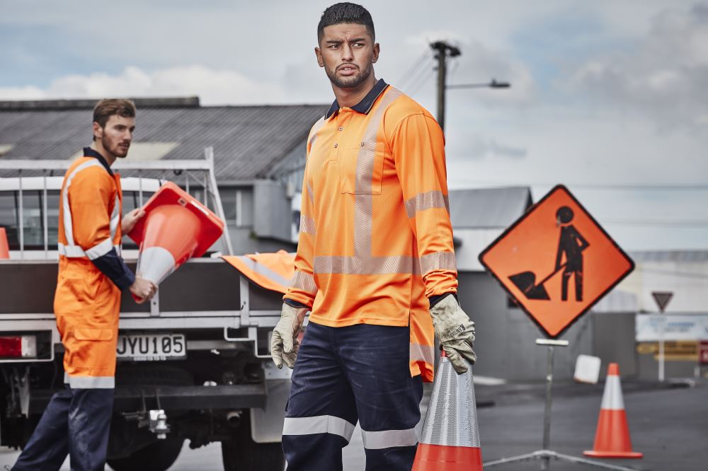 Mens TTMC W Segmented Long Sleeve Polo in orange and navy, featuring breathable fabric and a chest pocket for work practicality.