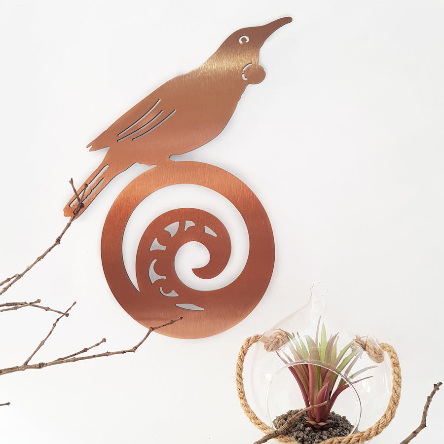 Kiwiana wall art featuring a Tui perched on koru in brushed copper, representing New Zealand's natural beauty and culture.