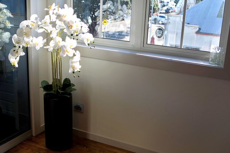 Lifelike white artificial orchid spray in a modern black pot, 135cm tall, perfect for elegant home or office decor.