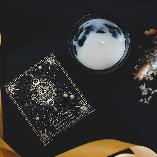 Eye of Providence manifestation candle in black frosted jar, featuring sage and white tea scents with gemstone chips.
