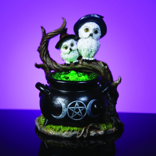 Cauldron-shaped LED light with two white owls in hats, green resin bubbles, and mystical design elements for enchanting decor.