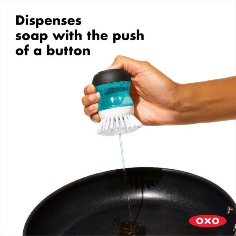 OXO Good Grips Soap Dispensing Palm Brush with ergonomic design and soap-on-demand feature for easy, efficient cleaning.