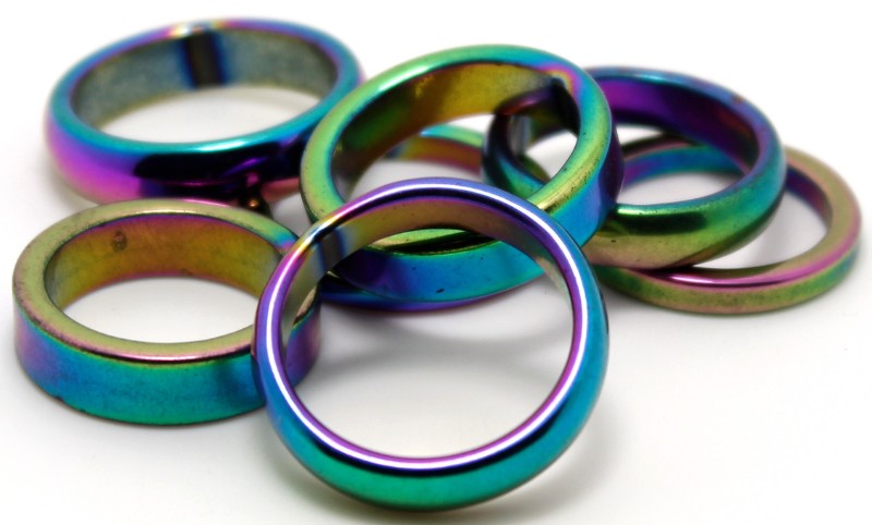 Pack of 100 Iridescent Hematite Rings in mixed sizes, showcasing vibrant colors and promoting emotional healing and creativity.