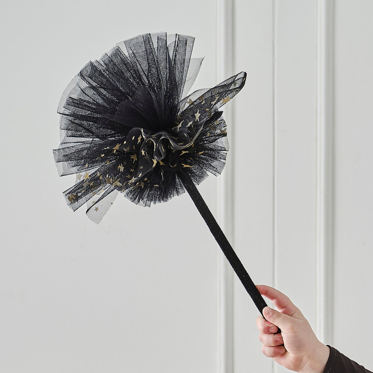 Whimsical black witches broom adorned with shimmering gold stars, perfect for Halloween costumes and imaginative play.