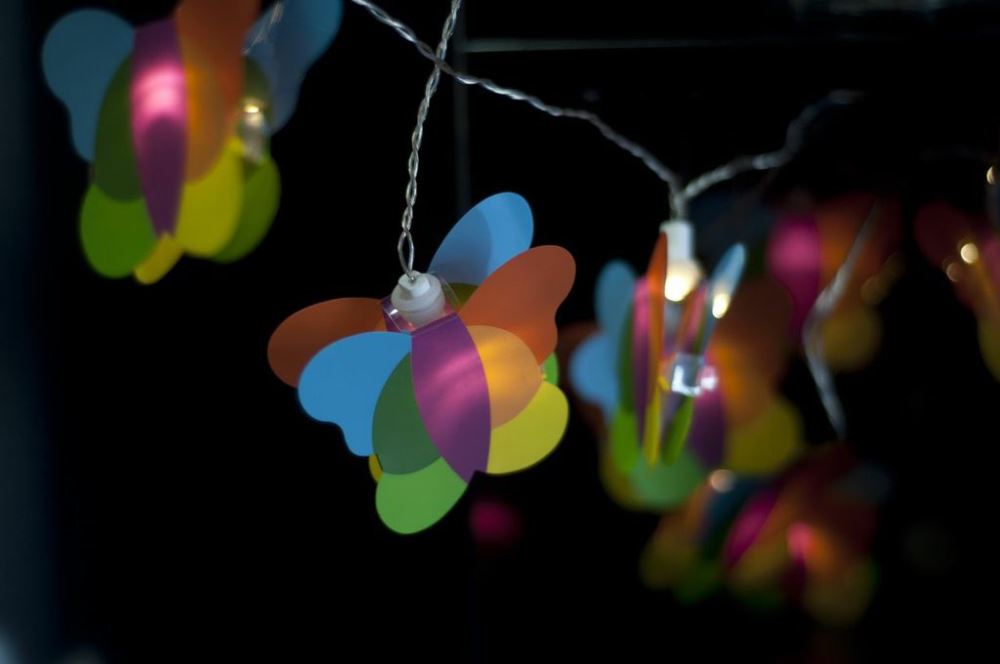 Colorful butterfly fairy lights on a clear wire, perfect for creating a magical ambiance in children's rooms and parties.
