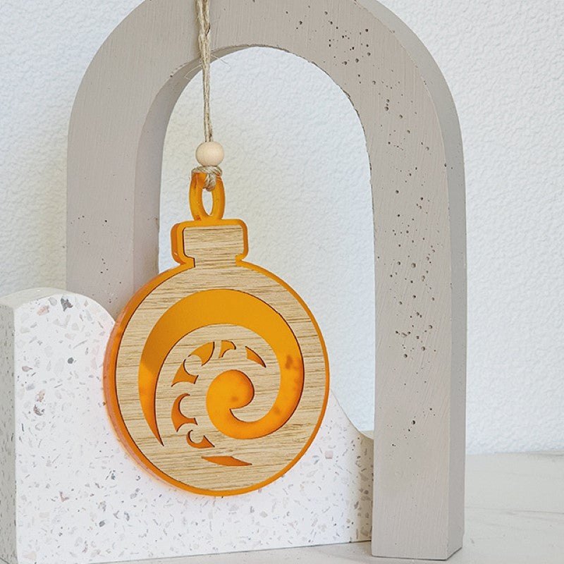 Vibrant orange satin acrylic hanging ornament featuring a koru design, symbolizing growth and new beginnings.