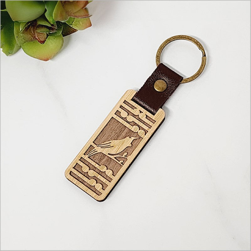 Bamboo keyring featuring Tui bird and Koru pattern, eco-friendly and lightweight, perfect gift or keepsake.