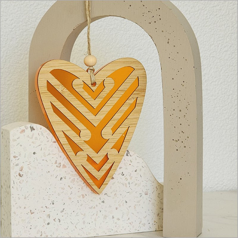 Heart-shaped orange satin acrylic ornament featuring intricate Koru designs, ideal for home decor and gifting.