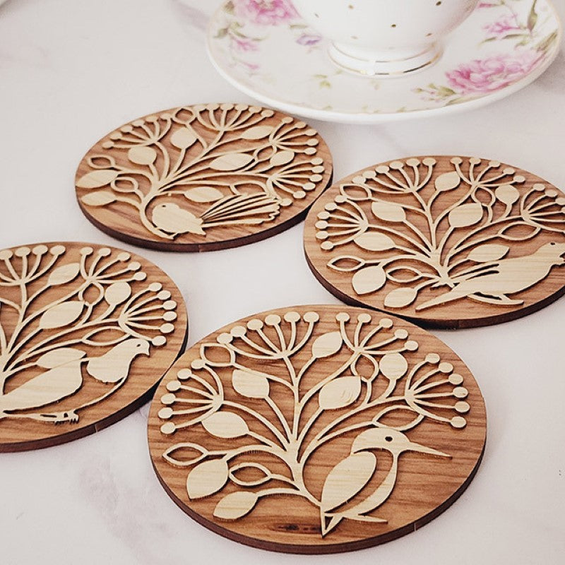 Bamboo and Rimu coasters featuring Pohutukawa designs and NZ birds, perfect for protecting surfaces and enhancing decor.