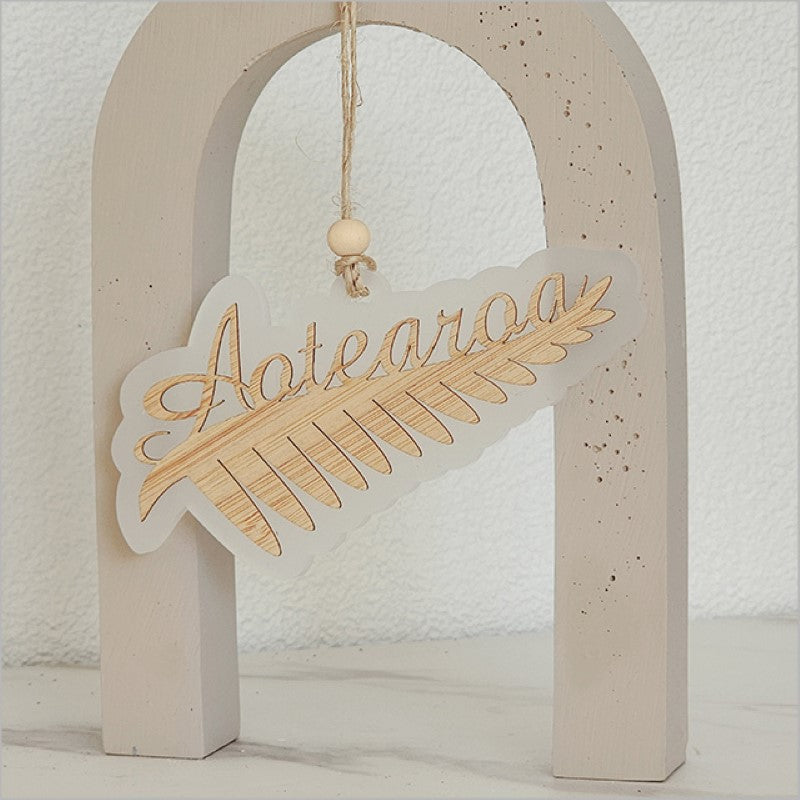 Hanging ornament featuring a silver fern design, crafted from white satin acrylic, ideal for festive decor and gifting.