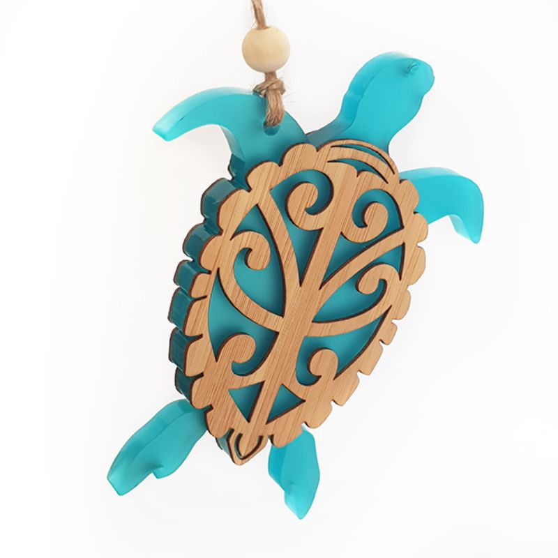 Hanging turtle ornament crafted from bamboo and teal satin acrylic, featuring intricate laser-cut designs for eco-friendly decor.