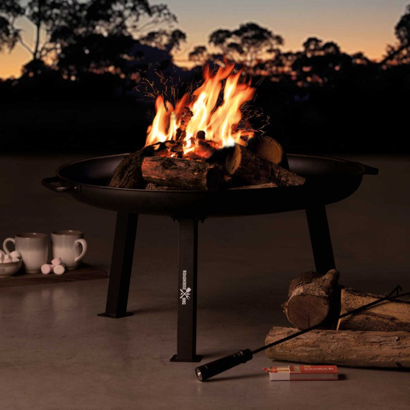 Black powder-coated steel fire pit with side handles, engraved logo, and charcoal rake, perfect for outdoor gatherings.