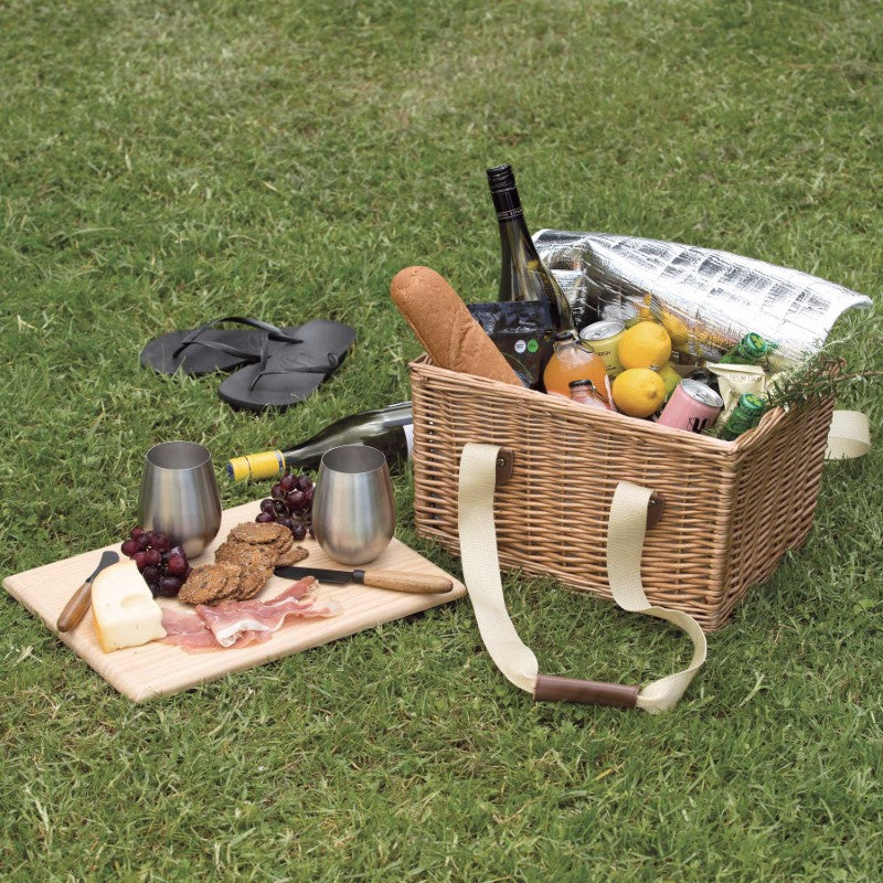 Wicker picnic basket with insulated cooler, removable pine lid serving board, and leather-wrapped handles for outdoor dining.