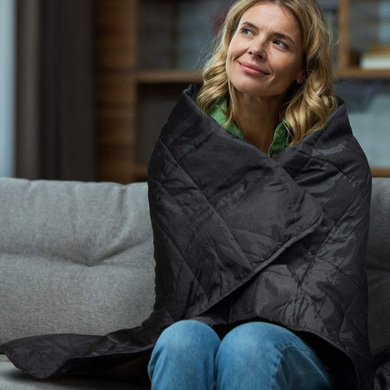 Cozy black puffer blanket, water-resistant with plush foam filling, perfect for indoor and outdoor comfort, includes drawstring pouch.