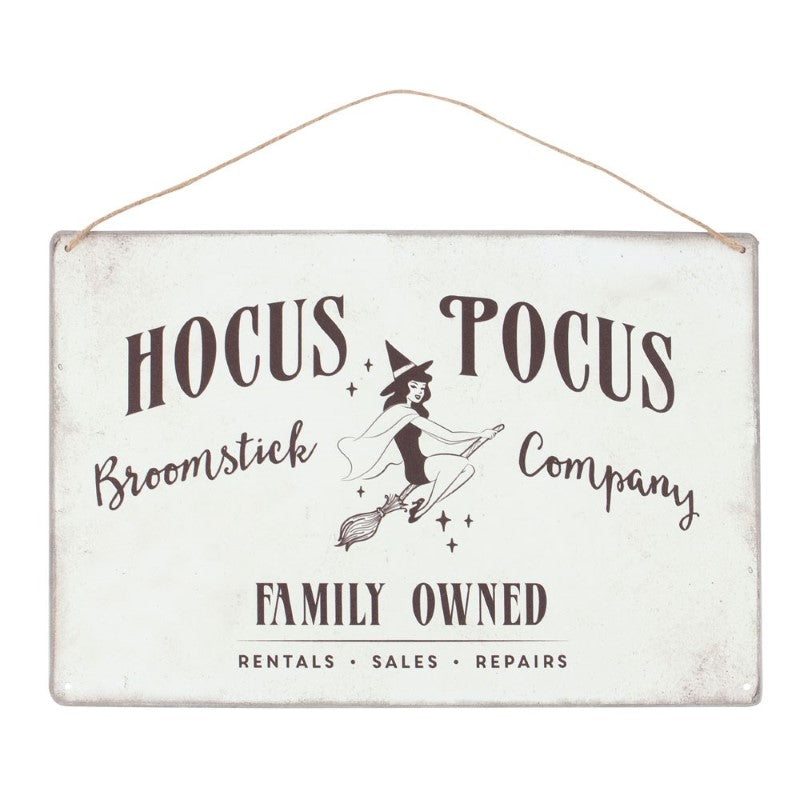 Retro metal sign featuring a pin-up witch illustration and 'Hocus Pocus Broomstick Company' text, ideal for Halloween decor.
