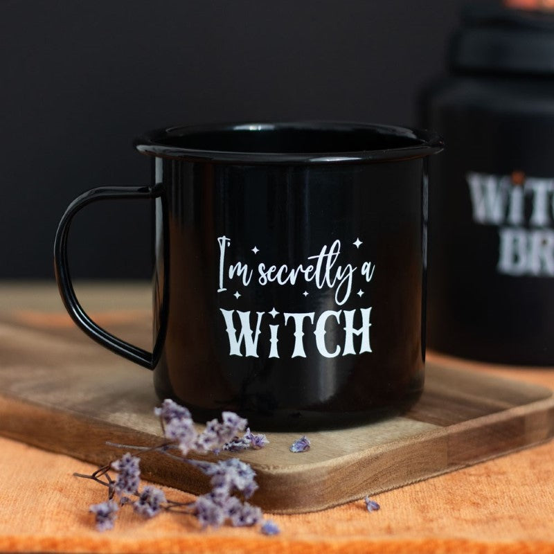Enamel mug with "I'm Secretly A Witch" text on a black base, ideal for hot beverages and Halloween-themed decor.