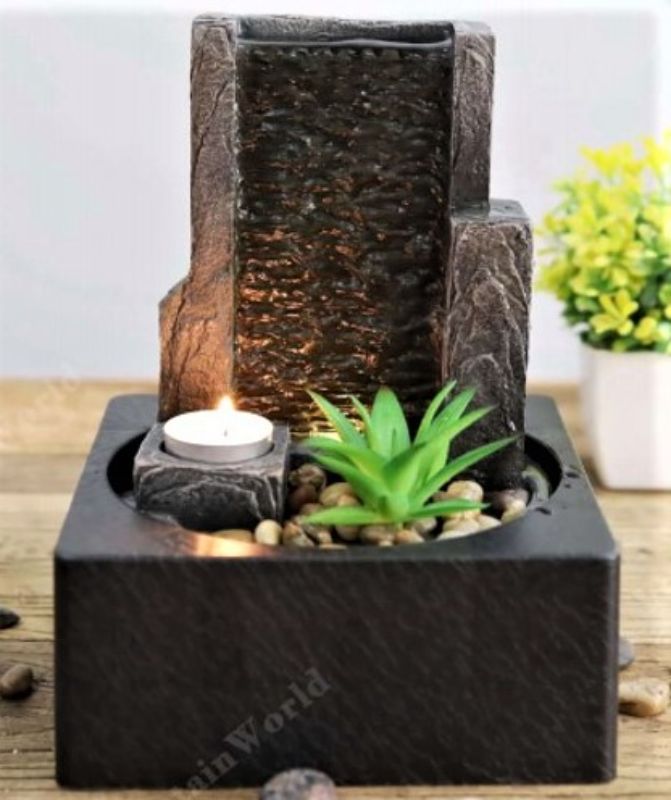 Ornamental water feature with cascading water, candle, and plant creating a tranquil ambiance in a stylish 25cm design.