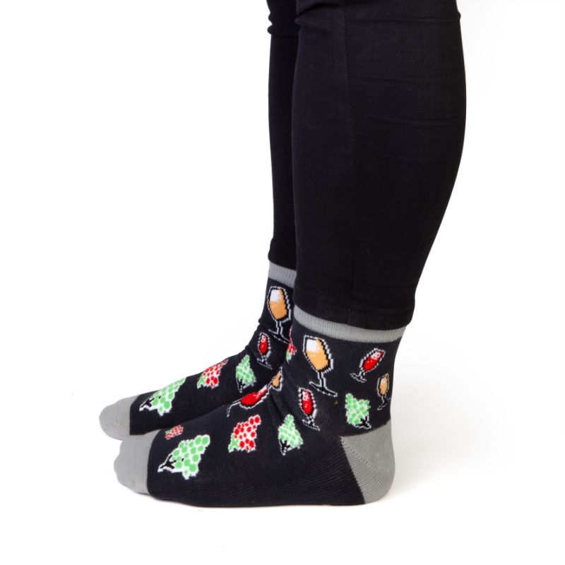 Fun wine-themed socks with illustrations of glasses and grapes, featuring 'WINE TIME' on the bottom for comfy lounging.