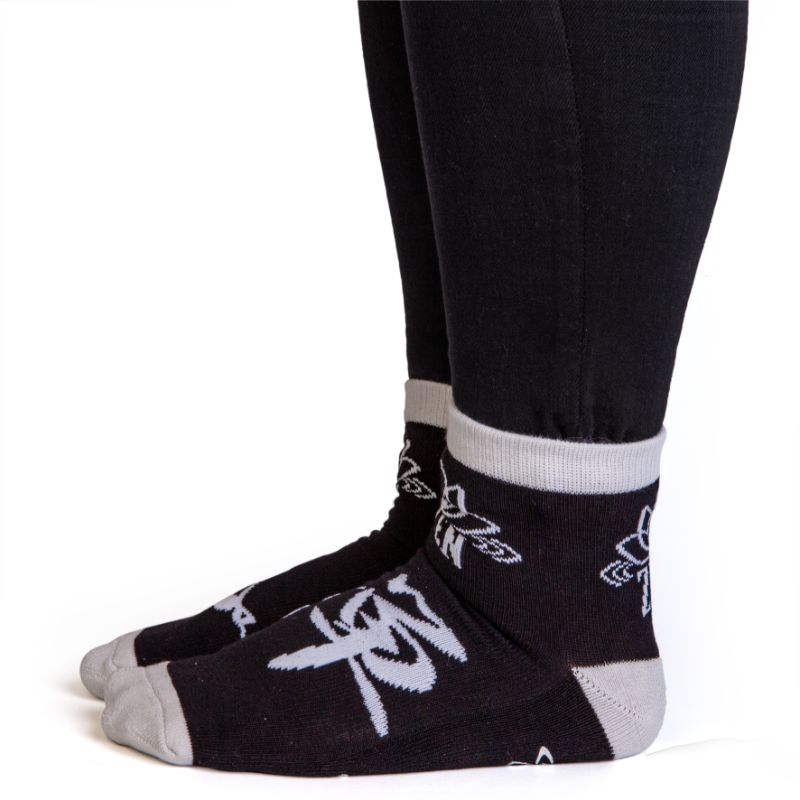 Black socks with a grey meditating silhouette, featuring an anti-slip design, ideal for style and mindfulness.