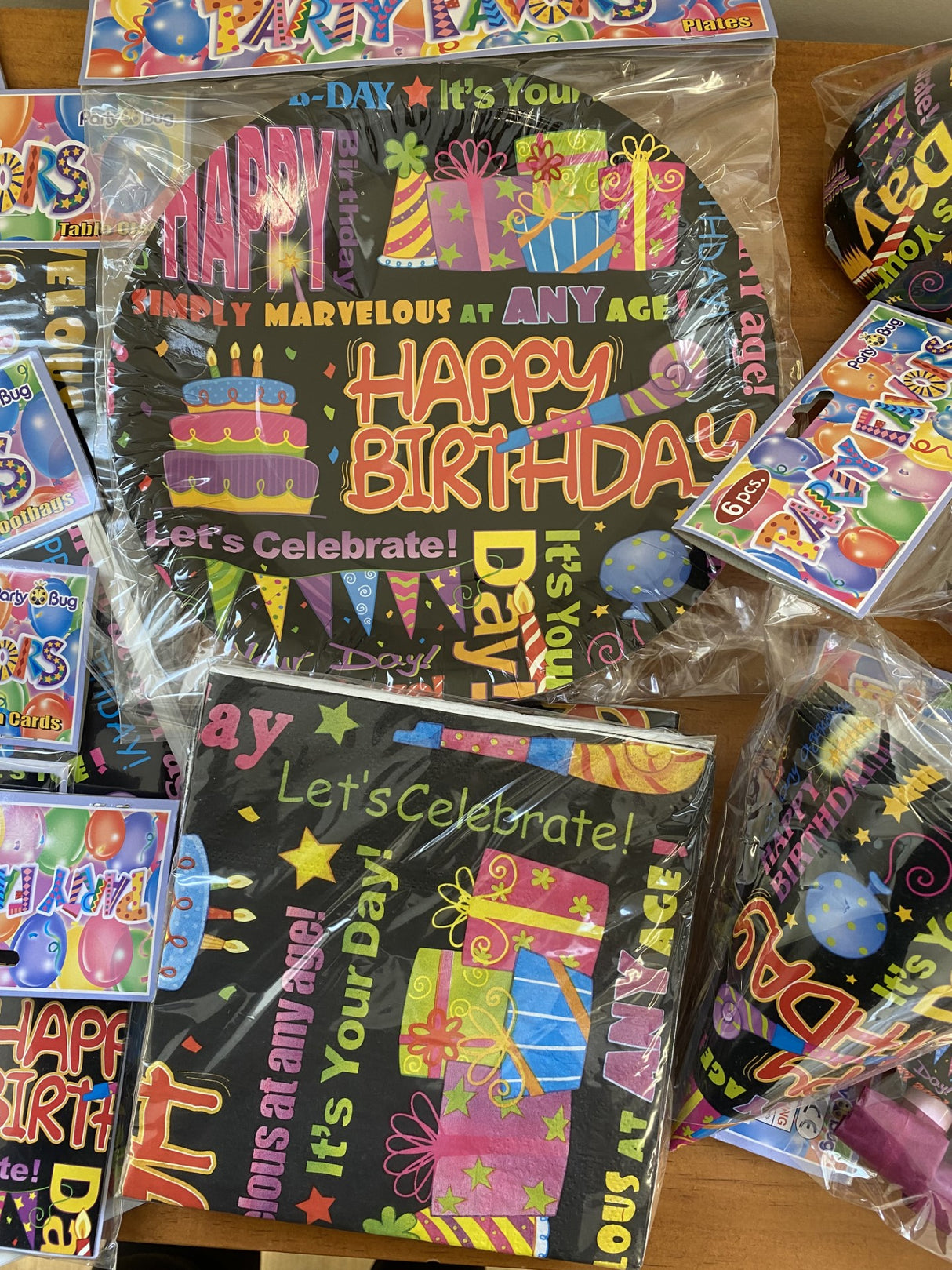 Vibrant party tableware set for birthdays, including napkins, plates, cups, hats, blowouts, and invitation cards.