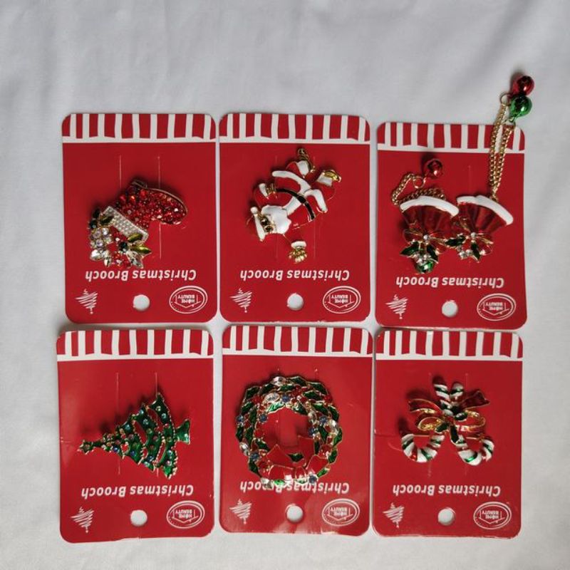 Colorful set of 12 Christmas-themed brooches featuring snowflakes, reindeer, trees, and Santa for festive holiday outfits.