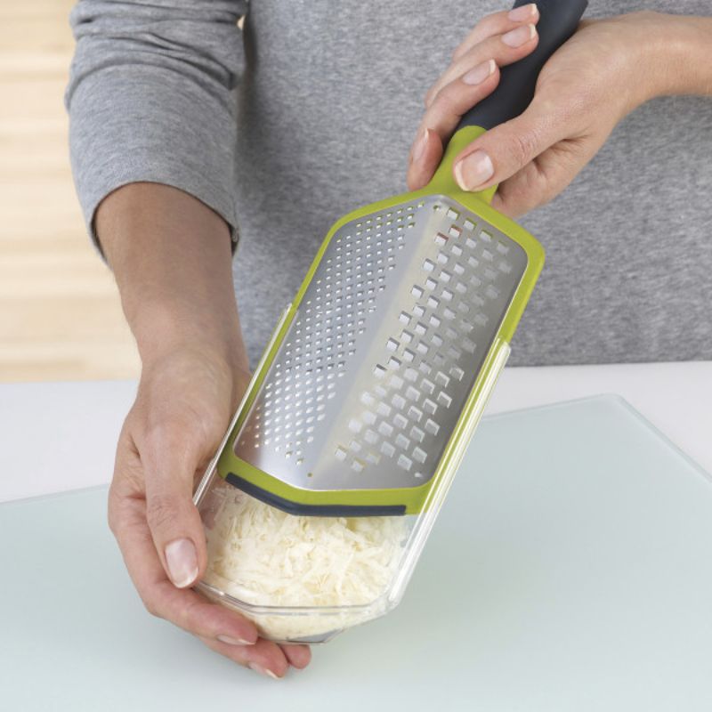 Joseph Joseph Twist Grater in green with coarse and fine blades, non-slip handle, and reversible sheath for easy grating and storage.