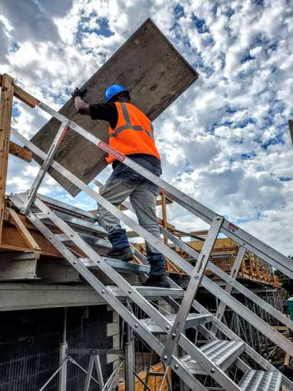 Adjustable aluminum safety stair with 18 self-leveling steps, designed for safe access between heights and easy storage.