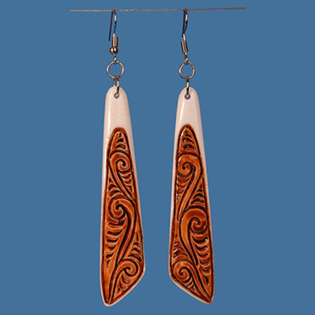Handcrafted Maori drop earrings in beef bone with stained koru patterns, celebrating craftsmanship and cultural significance.