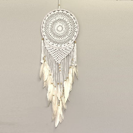 White crochet macrame dreamcatcher with beads and feathers, perfect for bohemian decor and creating a serene atmosphere.