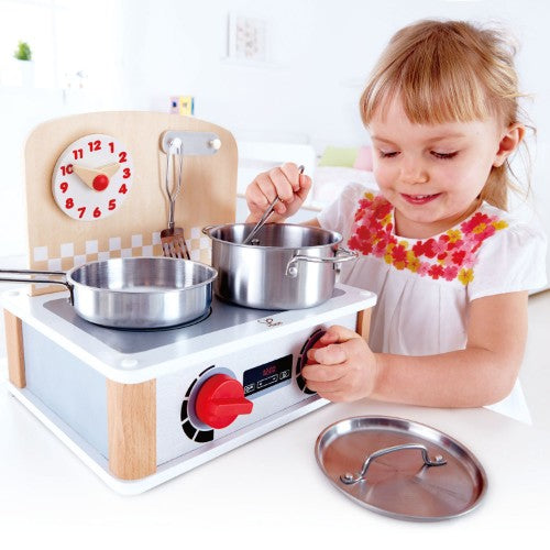 Realistic Hape 2-in-1 Kitchen & Grill Set with metal accessories, knobs, and adjustable clock for role-play cooking fun.