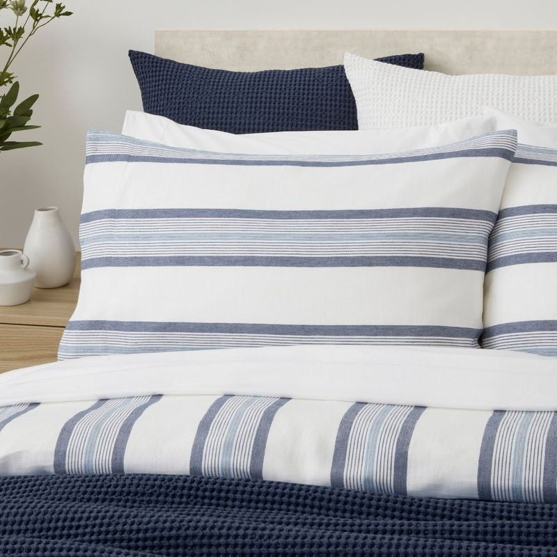 Blue and white striped duvet cover set with matching pillowcases, made from certified cotton and linen, ethically produced in Portugal.