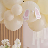 Pastel balloon arch kit with bunny feet decor for Easter celebrations, featuring 50 mixed-size balloons and eco-friendly packaging.