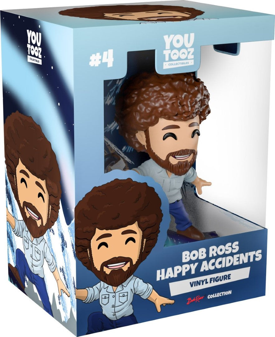 Bob Ross collectible figurine holding a paintbrush, surrounded by snowy mountains and pine trees, celebrating creativity.