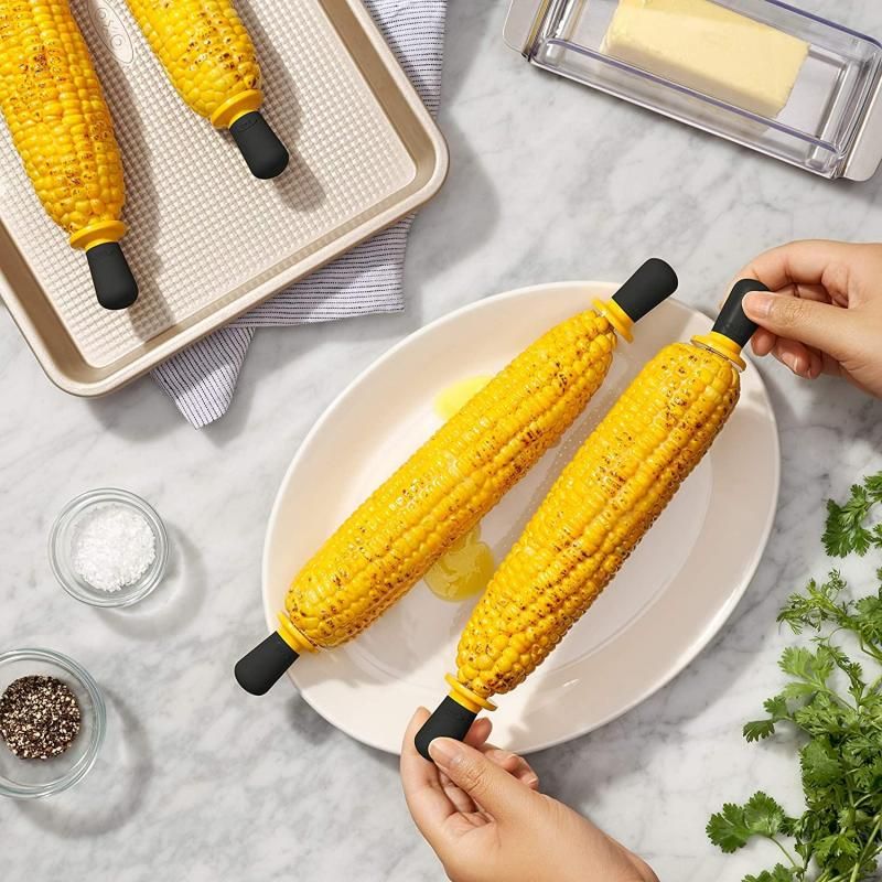 OXO Good Grips Corn Holders with stainless steel pins, non-slip handles, and butter barrier for mess-free corn enjoyment.