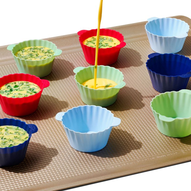 Vibrant 12-pack of OXO silicone baking cups, BPA-free, non-stick, ideal for muffins, cupcakes, and snacks with easy release tabs.