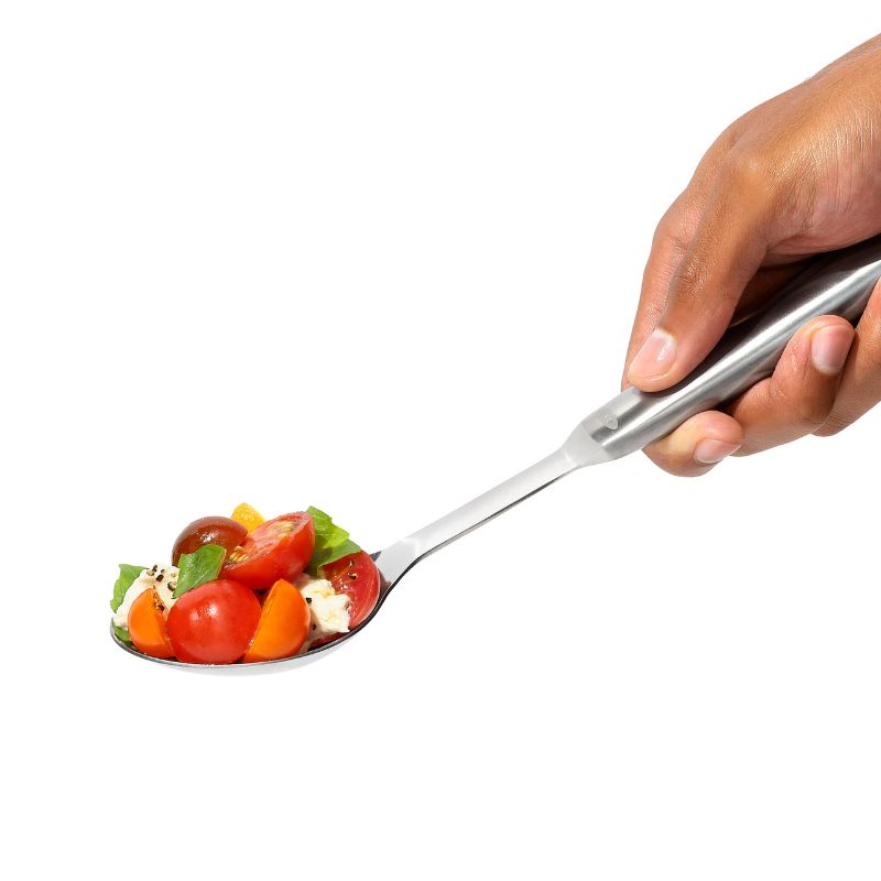 Sleek stainless steel serving spoon with deep well and angled head for easy scooping and serving of sides and sauces.